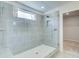 Bright bathroom shower with gray tile, glass door, and a small window at 249 Chiswick Loop, Stockbridge, GA 30281