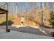 Brick patio featuring outdoor fireplace with stone surround, and landscaping in wooded backyard at 9625 River Lake Dr, Roswell, GA 30075