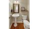 Classic powder room with a pedestal sink, decorative mirror, and a traditional-style toilet with hardwood flooring at 9625 River Lake Dr, Roswell, GA 30075