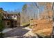 Back exterior view featuring a stone chimney, a covered patio, an upper balcony, and brick patio at 9625 River Lake Dr, Roswell, GA 30075