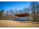 Outdoor pavilion in a park with a covered stage, open field, and wooded surroundings at 9625 River Lake Dr, Roswell, GA 30075