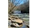 Picturesque river view featuring a waterfall, clear skies, trees, large rocks and tranquil water at 9625 River Lake Dr, Roswell, GA 30075