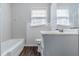 Well lit bathroom with white tub, toilet, sink and paneled walls at 8523 Duncan St, Douglasville, GA 30134