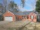 Traditional brick home with a two-car garage and a cozy front porch seating area at 5228 Boone Ct, Villa Rica, GA 30180