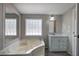 Bathroom showcasing a large tub, glass block window, vanity with marble top, and wood-look flooring at 62 W Lakeview Dr, Temple, GA 30179