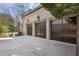Three-car garage featuring wood doors, stone accents, and ample parking space, complementing the brick exterior at 3871 Trickum Road Ne, Marietta, GA 30066
