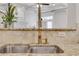 Close up on a stainless steel kitchen sink with a stylish faucet and a granite countertop with tiled backsplash at 3871 Trickum Road Ne, Marietta, GA 30066