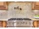 Close-up of a professional grade stainless steel stovetop with six burners and a tiled backsplash with pot filler faucet at 3871 Trickum Road Ne, Marietta, GA 30066