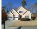 Charming two-story home with a manicured lawn, a two-car garage, and a welcoming front entrance at 1445 Oglethorpe Run Ln, Suwanee, GA 30024