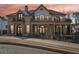 Elegant brick home with a charming front yard, second story terraces, and manicured landscaping at dusk at 440 Belada Blvd, Sandy Springs, GA 30342