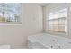Bathroom featuring a soaking tub with white tile surround and a window for natural light at 6165 Picketts Nw Rdg, Acworth, GA 30101