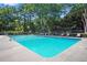 A bright blue swimming pool is surrounded by lounge chairs and lush green trees and shrubs in this full shot at 1501 Clairmont Rd # 1024, Decatur, GA 30033