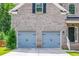 Close-up of a two-car garage and brick facade of the home with black door and sidelight at 3540 Lindsy Brook, Douglasville, GA 30135