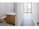 Modern bathroom with a wooden vanity, white countertops, and views of the city skyline from a large window at 2425 Peachtree Nw Rd # 1802, Atlanta, GA 30305