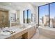 Spa-like bathroom with dual sinks, modern vanity, soaking tub, and stunning city views from the oversized window at 2425 Peachtree Nw Rd # 1802, Atlanta, GA 30305
