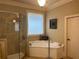 Bathroom featuring soaking tub, walk-in shower, and a large window allowing for plenty of natural light at 8440 Woodland Brooke Trl, Cumming, GA 30028