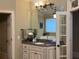 Bathroom featuring a vanity with granite countertops, a framed mirror, and an adjacent door at 8440 Woodland Brooke Trl, Cumming, GA 30028