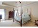 Comfortable bedroom with four-poster bed, neutral carpet, and a tray ceiling adding architectural detail at 8440 Woodland Brooke Trl, Cumming, GA 30028