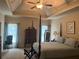 Bedroom featuring tray ceiling, four poster bed, and natural light at 8440 Woodland Brooke Trl, Cumming, GA 30028