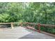 Relax on this wooden deck surrounded by a lush green backyard with mature trees and bird feeders at 8440 Woodland Brooke Trl, Cumming, GA 30028