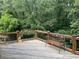 Outdoor deck with wooden railings, a bench, and a view of lush greenery, ideal for relaxation and entertaining at 8440 Woodland Brooke Trl, Cumming, GA 30028