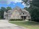 Stately brick home with a manicured lawn, mature trees, and a long driveway leading to attached two-car garage at 8440 Woodland Brooke Trl, Cumming, GA 30028