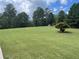 Expansive green lawn leading up to a grand residence surrounded by mature trees at 8440 Woodland Brooke Trl, Cumming, GA 30028