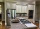 Kitchen with granite counters, stainless steel appliances, and a center island with cooktop at 8440 Woodland Brooke Trl, Cumming, GA 30028
