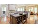 A spacious kitchen featuring an island with a cooktop, granite countertops, and stainless steel appliances at 8440 Woodland Brooke Trl, Cumming, GA 30028