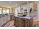 A modern kitchen featuring an island cooktop, stainless steel appliances, and an adjacent staircase at 8440 Woodland Brooke Trl, Cumming, GA 30028