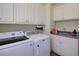 Bright laundry room with modern washer, dryer, granite countertop, sink, and white cabinetry at 8440 Woodland Brooke Trl, Cumming, GA 30028
