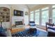 Vaulted living room with fireplace, built-in shelving, large windows, and hardwood flooring at 8440 Woodland Brooke Trl, Cumming, GA 30028