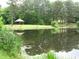 Calm pond reflecting lush trees and a gazebo, creating a serene recreational space at 8440 Woodland Brooke Trl, Cumming, GA 30028
