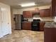 Functional kitchen with dark wood cabinets, black appliances, and tile flooring at 304 Morning Star Drive Dr, Temple, GA 30179