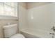 A clean, tiled bathtub in a bathroom with a nearby toilet and a window at 5498 Balmoral Dr, Douglasville, GA 30135