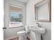 Elegant half bath featuring a modern pedestal sink, mirror and a window at 745 Great Oak Pl, Villa Rica, GA 30180