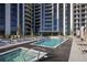 Luxury swimming pool and hot tub area with lounge chairs, umbrellas, and a modern high-rise building in the background at 2425 Peachtree Ne Rd # 903, Atlanta, GA 30305
