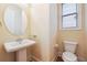 Charming powder room featuring a pedestal sink, modern faucet, toilet, and natural light at 33 Hardpan Aly, Marietta, GA 30066