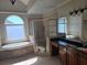 Bathroom features a tub beneath an arched window, a glass-enclosed shower, and a granite-topped vanity at 4520 Mossey Dr, Lithonia, GA 30038