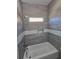 Modern bathroom with gray tiled walls and a tub featuring a built in shelf at 4520 Mossey Dr, Lithonia, GA 30038