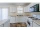 Well-lit kitchen with white cabinets and appliances, plus a double sink and laminate countertops at 6138 Raleigh Oaks Ct, Lithonia, GA 30058