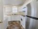 Well-lit kitchen with white cabinets and stainless steel refrigerator, plus a double sink and laminate countertops at 6138 Raleigh Oaks Ct, Lithonia, GA 30058