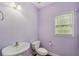 Powder room with lavender walls features modern fixtures and a window at 2143 Great Shoals Cir, Lawrenceville, GA 30045
