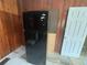 Black refrigerator sits against the wall, next to a wooden cabinet and door at 1907 Langston Sw Ave, Atlanta, GA 30310