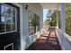 Inviting covered porch with wood floors, white railings, and a view of the surrounding trees at 3550 Beaver Cove Rd, Cumming, GA 30041