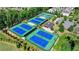 Aerial view of multiple, well-maintained tennis courts surrounded by lush greenery in the community at 951 Olmsted Ln, Johns Creek, GA 30097