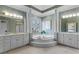 Large main bathroom with dual vanities, a large soaking tub, and elegant architectural details at 8210 Sentinae Chase Dr, Roswell, GA 30076