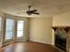 Bright living room with a stone fireplace, ceiling fan, and natural light from bay windows at 3636 Hopkins Ct, Powder Springs, GA 30127