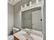 The bathroom includes a wide mirror, sleek lighting fixtures, a toilet and white cabinets at 1064 Wenham Ln, Lawrenceville, GA 30044