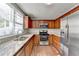 Well-lit kitchen boasts stainless steel appliances, granite countertops, and wood cabinets at 1064 Wenham Ln, Lawrenceville, GA 30044